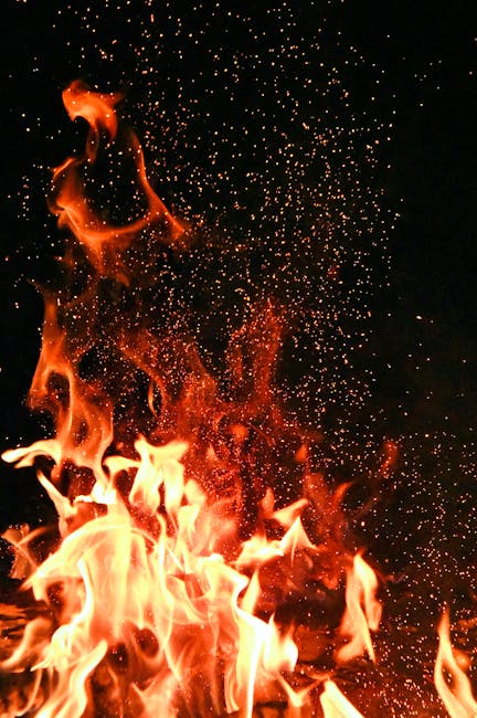 Vivid orange flames and sparks dance against a mysterious black backdrop.